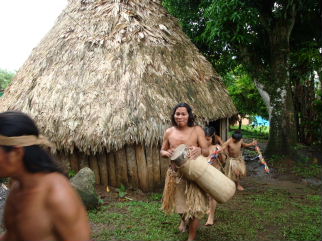 Maleku Indians in bark cloth dress leaving traditional grass hut in the village of Tonjibe, Costa Rica