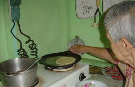 Hortensia in her Atenas, Costa Rica kitchen browning a tortilla on a hot griddle (comal)
